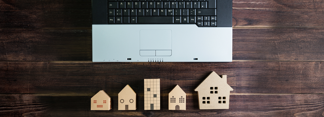 Træmodeller af huse ved siden af en laptop